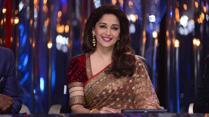 Madhuri Dixit looking beautiful in a maroon velvet blouse with puffed sleeves and a saree of beige net.