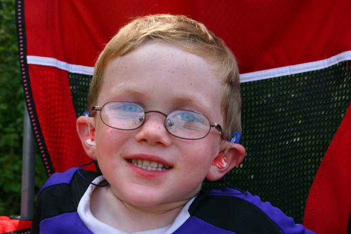 Blue neoprene sleeves cover our son's hearing aids to prevent moisture damage from sweat and light rain.