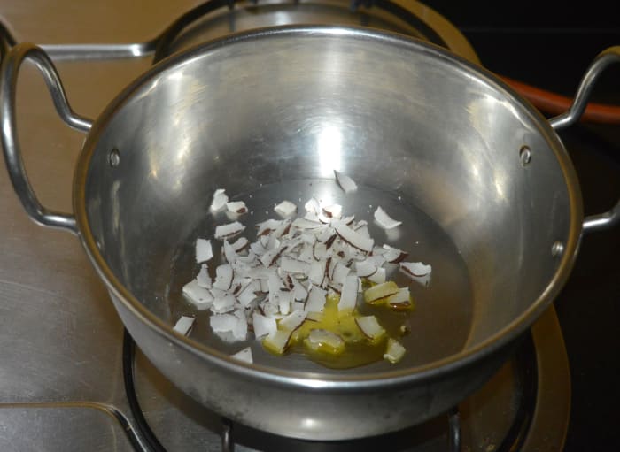 Step two: Slightly roast copra pieces and cashew nut pieces in ghee. Saute separately. Collect it on a plate.