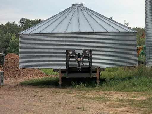 Iron supports were added to the sides of this trailer to stabilize this bin. For a bin which is much wider than your trailer and which you can haul safely in other respects, consider doing this.