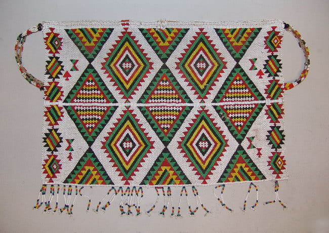 Zulu beaded apron made with tiny glass beadsDazzling geometric designs were created by use of the brick stitch. Triangles in this apron are recorded to represent traditional Zulu Shields