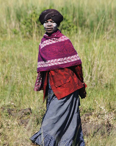 Xhosa woman wearing traditional Xhosa cloth of long skirts, embroidered with horizontal stripes and placed at varying intervals