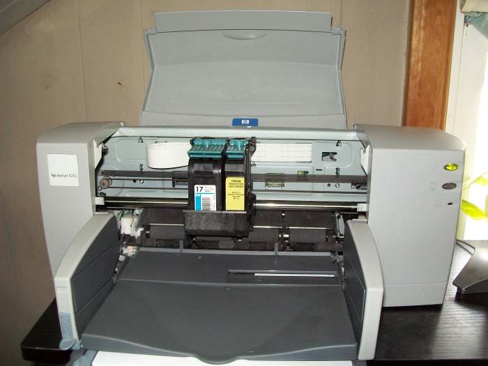 Open cover showing where the ink cartridges go. An empty color cartridge is still installed while a re-manufactured HP 15 Black ink cartridge is installed.