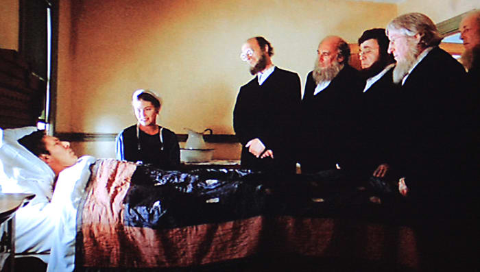 A recuperating John Book is visited by the elders of the community. The lighting in scenes such as this was inspired by the paintings of Vermeer with a single light source to one side, washing across the room and fading on the other side