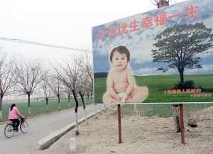 A woman cycles past a billboard encouraging couples to have only one child, along a road leading to a village in the suburbs of Beijing. China continues to enforce its one child policy to limit its huge population to 1.6 billion by 2050. (Goh Chai H