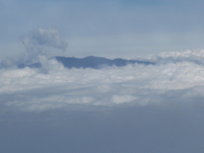 Summit of Mauna Kea or Mauna Loa poking through clouds as seen from an airplane