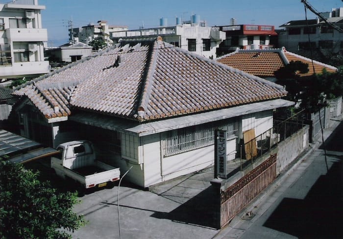 Traditional houses are often found alongside modern apartment buildings. This scene was taken in Isa, Ginowan, Okinawa.