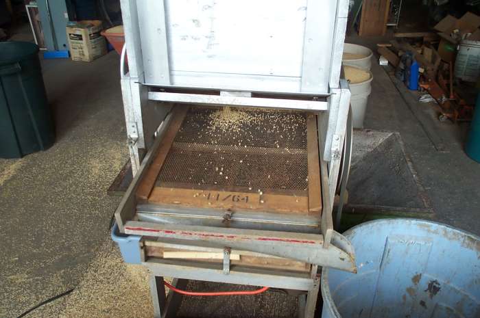 The fan mill electric motor is started, and the hopper is adjusted to let only a trickle of grain pass through.