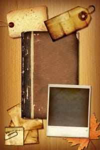 Aged scrapbook materials including a blank book, Polaroid photo, tags, and pieces of paper in sepia tones