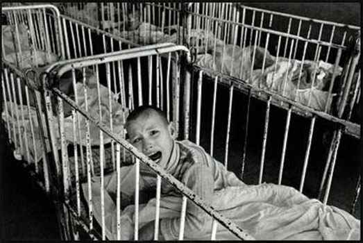 A Romanian orphan in the early 1990s, surrounded by other orphans. "Babies who don't get attention when they cry learn to stop crying."
