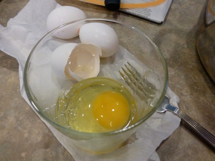 First, crack the egg into a glass. Inspect the top of the yolk and the white.