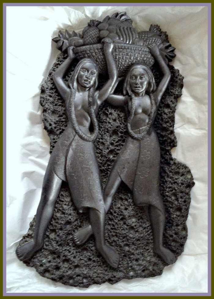 A vintage black lava Coco Joe wall décor plaque depicting two Hawaiian Hula Girls with a bowl of pineapples above their heads. It measures approximately 12" long and 7" at its widest. It weighs 2 lbs 5.0 oz. Makes a great addition to your tiki bar.