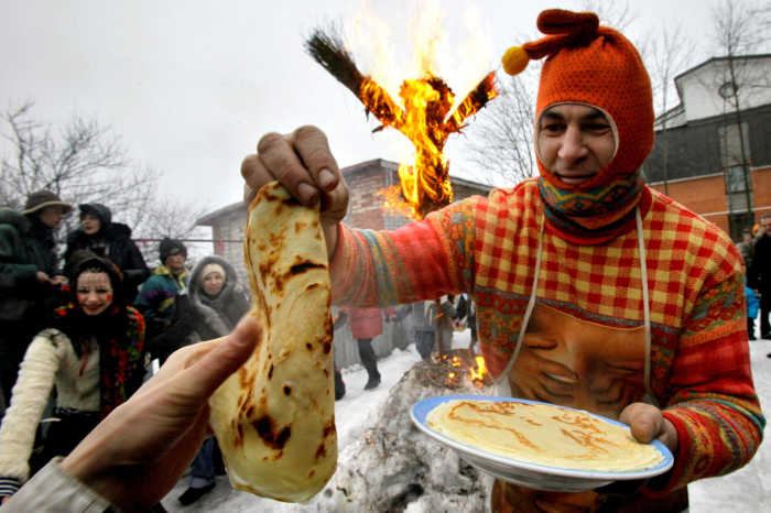 A man dressed as a "skomorokh", a medieval East Slavic harlequin, distributes bliny in St. Petersburg, Russia.