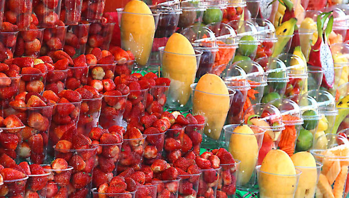 Fruits in the Chatuchak Street Market in Bangkok. Next to the strawberries are yellow peeled mangos and mixed fruits in plastic containers