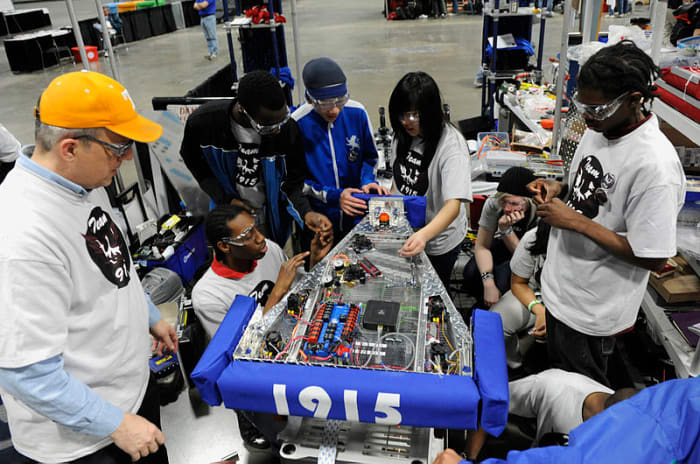 WASHINGTON (March 5, 2010) Cmdr. Jim Grove, from the Office of Naval Research Navy Reserve Program 38, left, helps students from McKinley Technology High School make adjustments to their robot during the For Inspiration and Recognition of Science and
