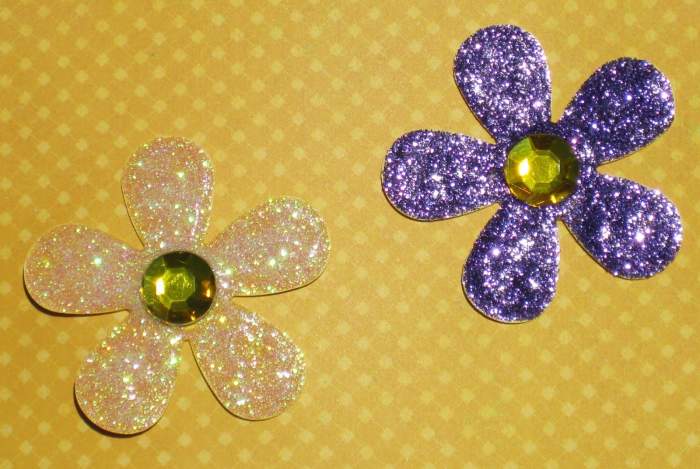 It is easy to create your own glitter glue flowers, Cut out a flower of your choice on heavy card stock. Paint the glitter glue on top of the flower petals, Allow to dry. Add a half gem to the top. Perfect for a scrapbook page or a card.