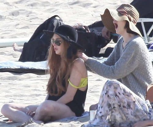 Even celebrities do it: Ali Lohan massages Lindsay Lohan's shoulders as they relax on the beach in Los Angeles.
