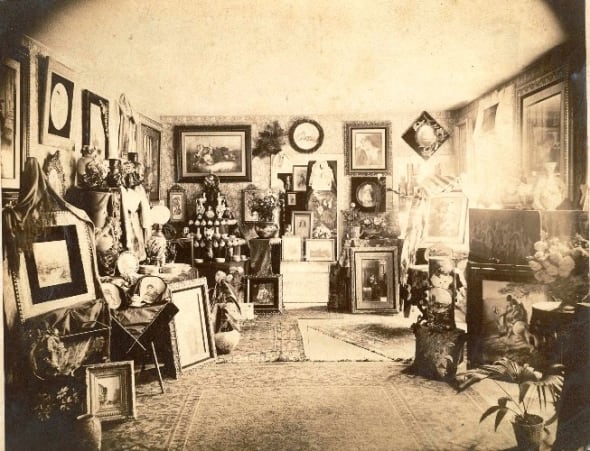 A period photo of a Victorian interior. Note the numerous framed pictures on the wall and the decorative objects on every available surface. Scroll down to see more room settings in our gallery of Victorian interiors.