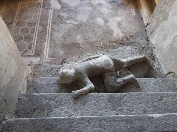 VII.16.17-22 Pompeii. December 2007. Plaster cast of body lying at foot of staircase. Four people met their death in this house, three of them died huddled together on this staircase. Cases were made from their skeletal remains