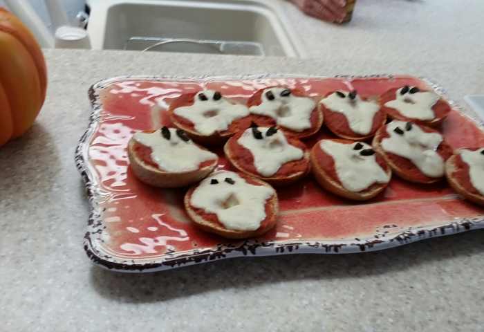 Get the miniature bagels, spread pizza sauce on them. Remove bits from mozzarella cheese to form ghost shapes. Heat until the cheese melts. Small bits of black olives can serve as eyes.