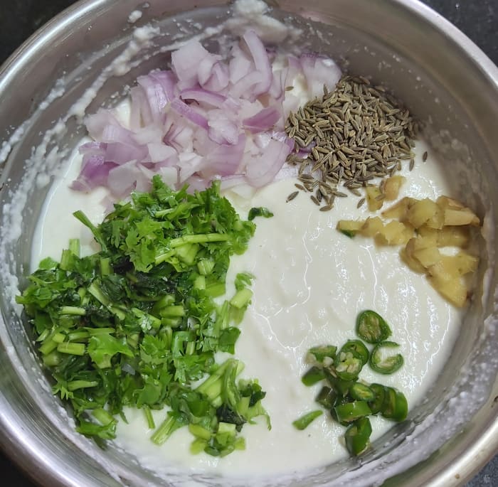 To this batter, add 1-2 finely chopped onions, 1 teaspoon cumin seeds, 2-3 tablespoons of finely chopped fresh coriander leaves, 1-2 finely chopped green chilies, 1 inch long finely chopped fresh ginger.