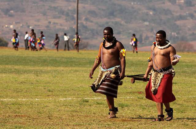 Swazi men corning their traditional wear and necklaces, carrying their cultural sticks on their way to a Swazi Reed festival