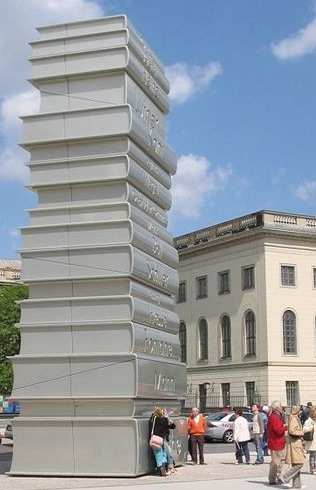 Gigantic Books symbolically towering over libraries as a sign of their being live and continuously in our midst