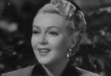 Lana Turner's round face is made more elegant by having her hair swept up and back.