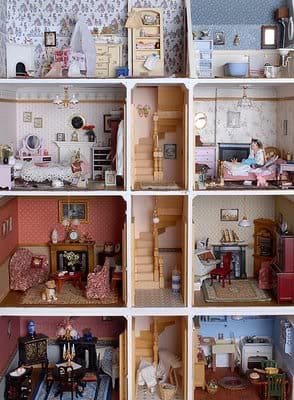 A vintage style 3-storey dollhouse with a central wooden spiral staircase, a parlour, fireplace, kitchen, bedrooms and bathroom.