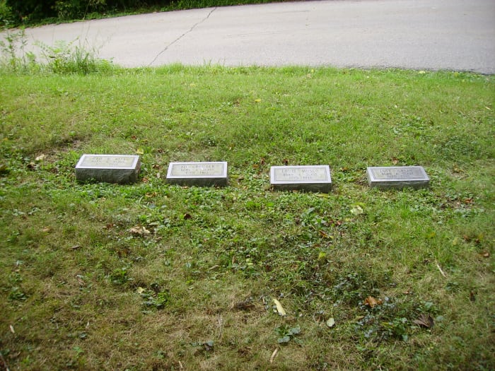 Four of the five replaced headstones, bearing the names of the men, along with the words "Born A Slave Died Free"