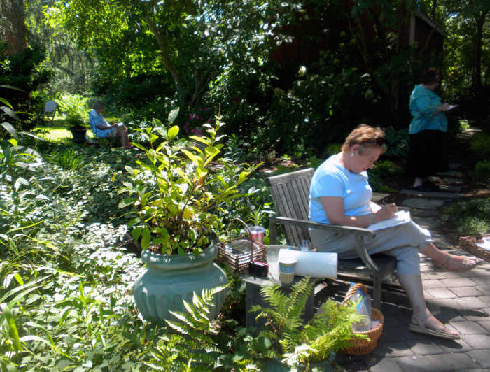 A student from the Waterview Gardens Workshop sits among the greenery as she sketches.
