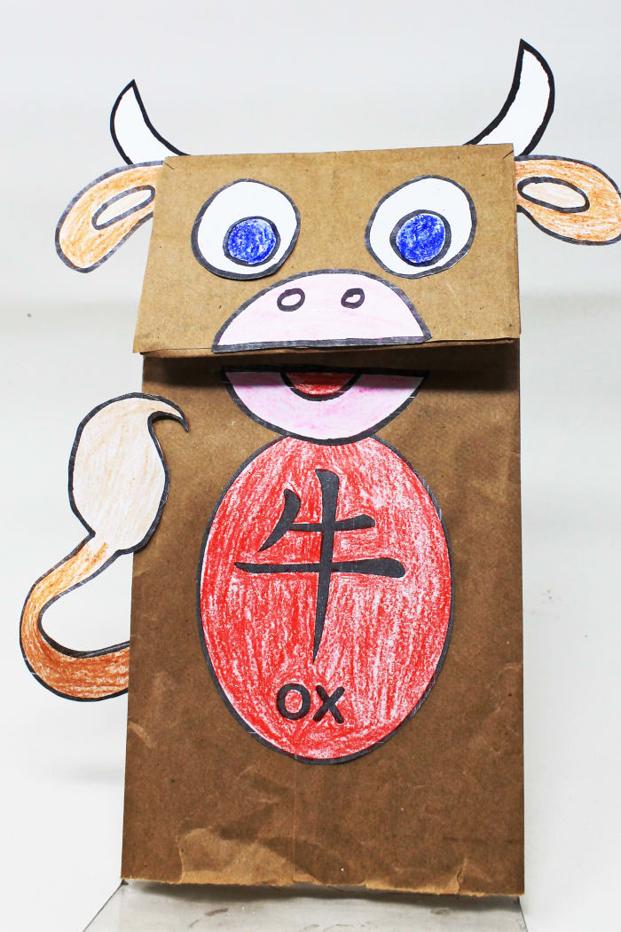 Using a printable template, children can color, cut, and assemble this Year of the Ox paper bag puppet.