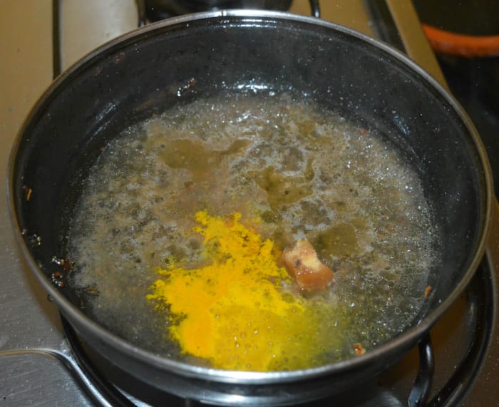 Step three: Heat the same pan once again. Add tamarind pulp, 1 cup of water, jaggery powder, and turmeric powder. Let the mixture come to a boil. Simmer for 1 minute.