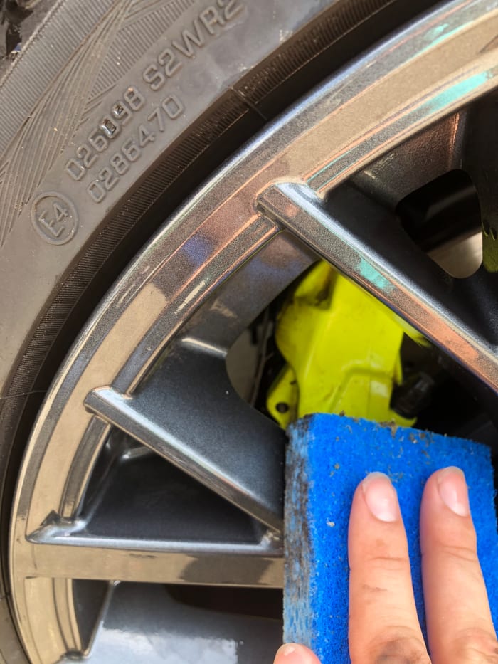 Brake dust does not come off with high pressure, or chemicals. The only way to get it off is elbow grease. I used an ordinary kitchen sponge. Use only soap and water on the ceramic brakes.