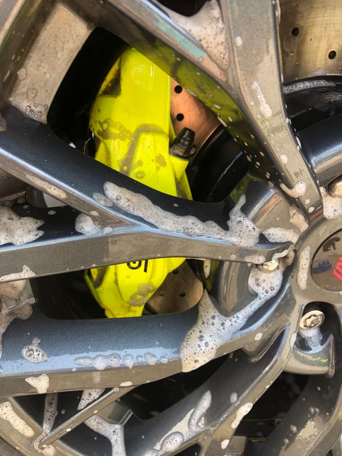 Brushy-brushy. You can use a harsher brush on your wheels than on the rest of the car, but if you have after market rims check with whoever installed them about what products you can use.