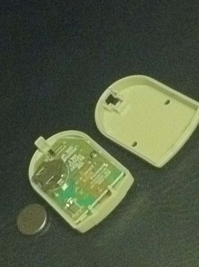 The garage door sensor consists of a simple circuit board, the two halves of its case, and a flat battery.
