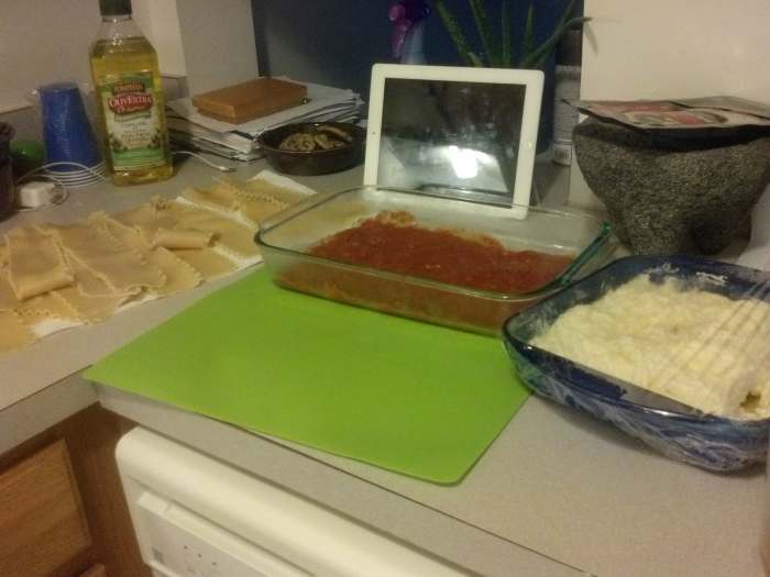 Laying out all of the ingredients can make it simpler and easier to form the lasagna rolls. From left to right: lasagna noodles on the paper towels drying, my baking pan with a layer of sauce ready to accept the rolls, and my filling. (Plus my iPad R