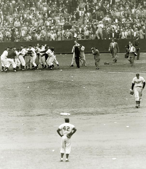 A rarely seen angle: The Giants mob Thomson as a dejected Ralph Branca starts the long walk to the visitors' locker room in center-field. Jackie Robinson stands in shock.
