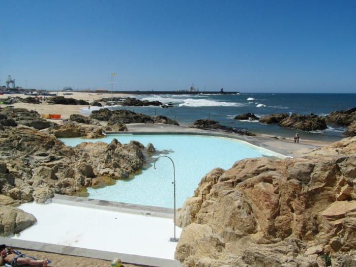 The shallow pool at Piscina das Mares, Leca da Palmeira, with the beach and harbour wall in the background.