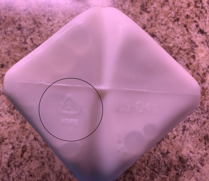 Bottom of a half gallon of milk that has a "2" inside a triangle with "HDPE" next to the triangle. This is recyclable High density polyethylene plastic.