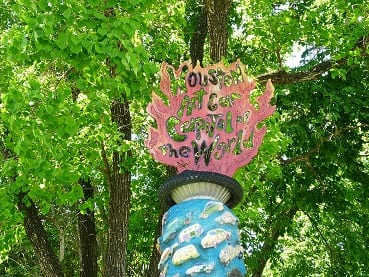 The top of a pillar in a yard across from the Orange Show Foundation has the following cutout design: Houston Art Car Capital of the World.