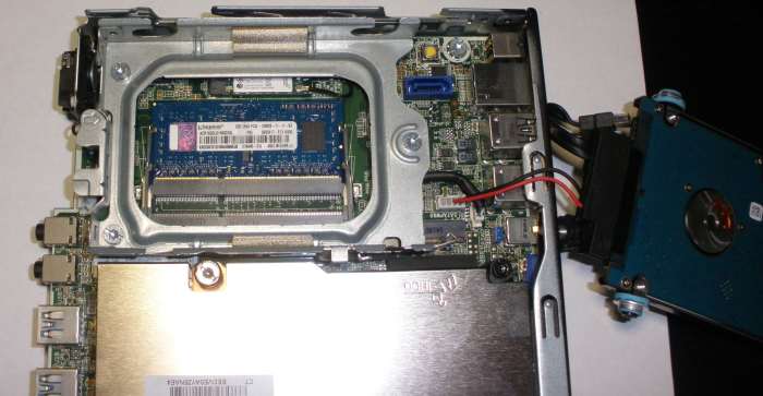 With the hard drive out of the way, we can now access the memory slots on this PC. Gently pry the tabs to the side of any existing modules if they are being replaced to allow them to spring up from the slot at an angle, then gently slide them out.
