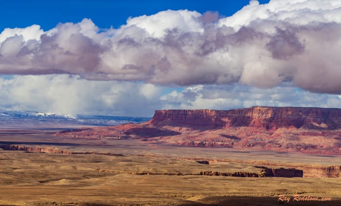 Wide angle view of the Vermilion cliffs and the snow bound North Rim of the Grand Canyon in the distance.