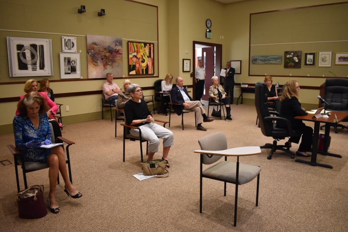 The gentleman sitting at the back of the room with arms folded is showing via body language that he likes to keep to himself and do not want to engage with other people.