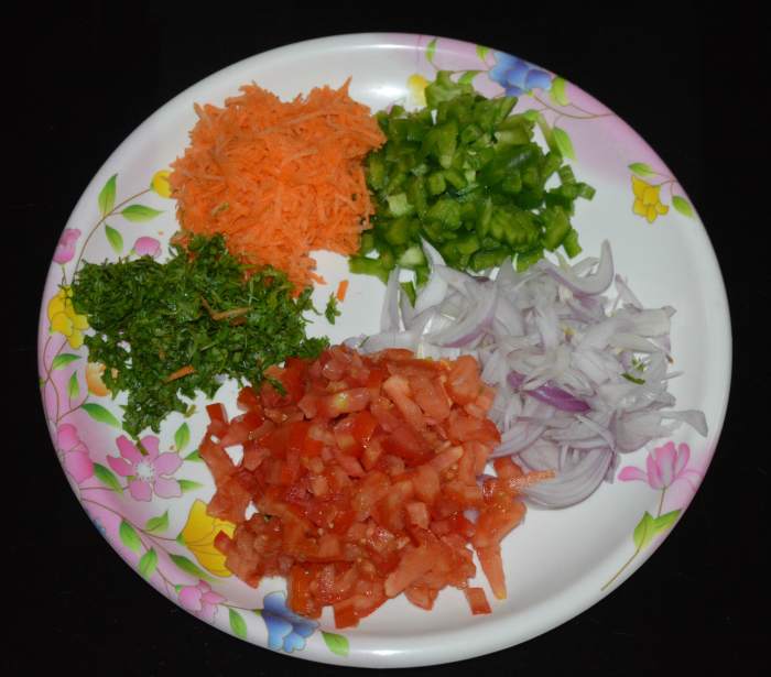 Step one: In a large mixing bowl, add chopped onions, capsicum, tomatoes, coriander leaves, and grated carrot.
