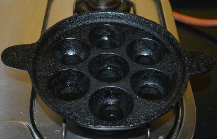 Step five: Heat a pan with cavities. Keep the heat at medium-high. Add a quarter teaspoon oil to each cavity. Place a ball in each cavity. Keep turning each of them occasionally with a spoon to ensure uniform roasting on all sides.