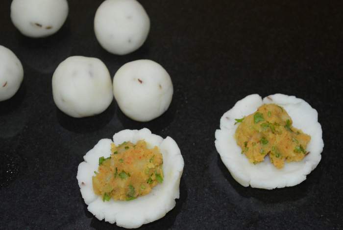 Divide the stuffing to get an equal number of portions as the dough balls. Take one of the dough balls and form a cup. Fill one of the stuffing portions in it.