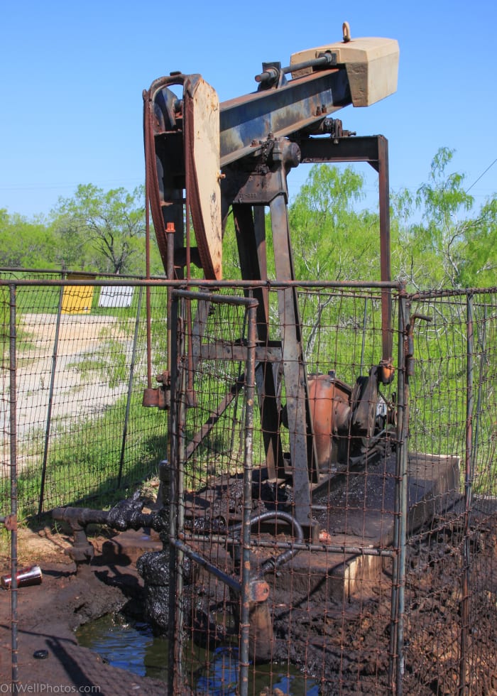 This old stripper well has gas bubbling up in a pool of oil at the base of the casing. This indicates that the casing is compromised at some point.