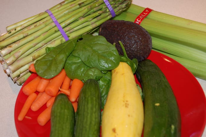 Assorted fresh vegetables: asparagus, carrots, spinach, avocado, cucumbers, yellow squash, zucchini, celery