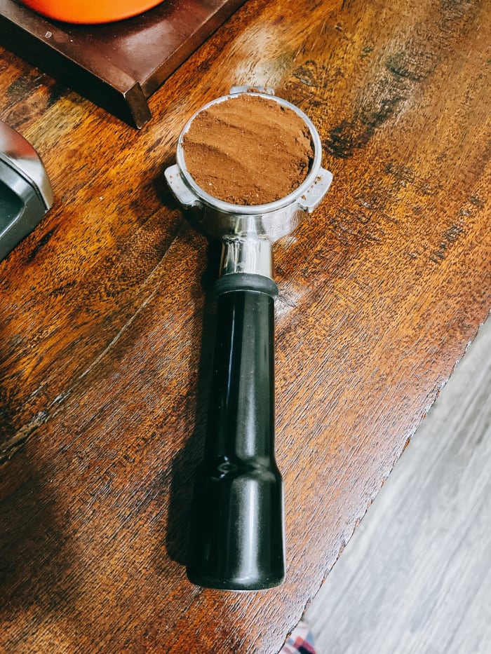 Dump your espresso grounds in the portafilter, aiming to distribute them evenly in the filter basket.